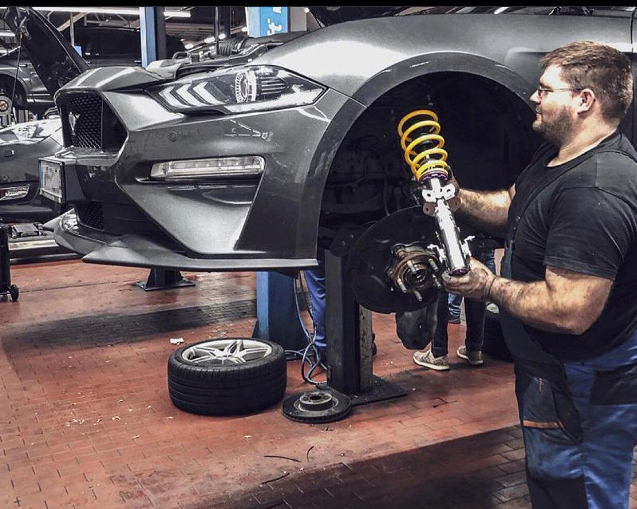 Eine Person arbeitet an der Vorderradaufhängung eines Ford Mustangs
