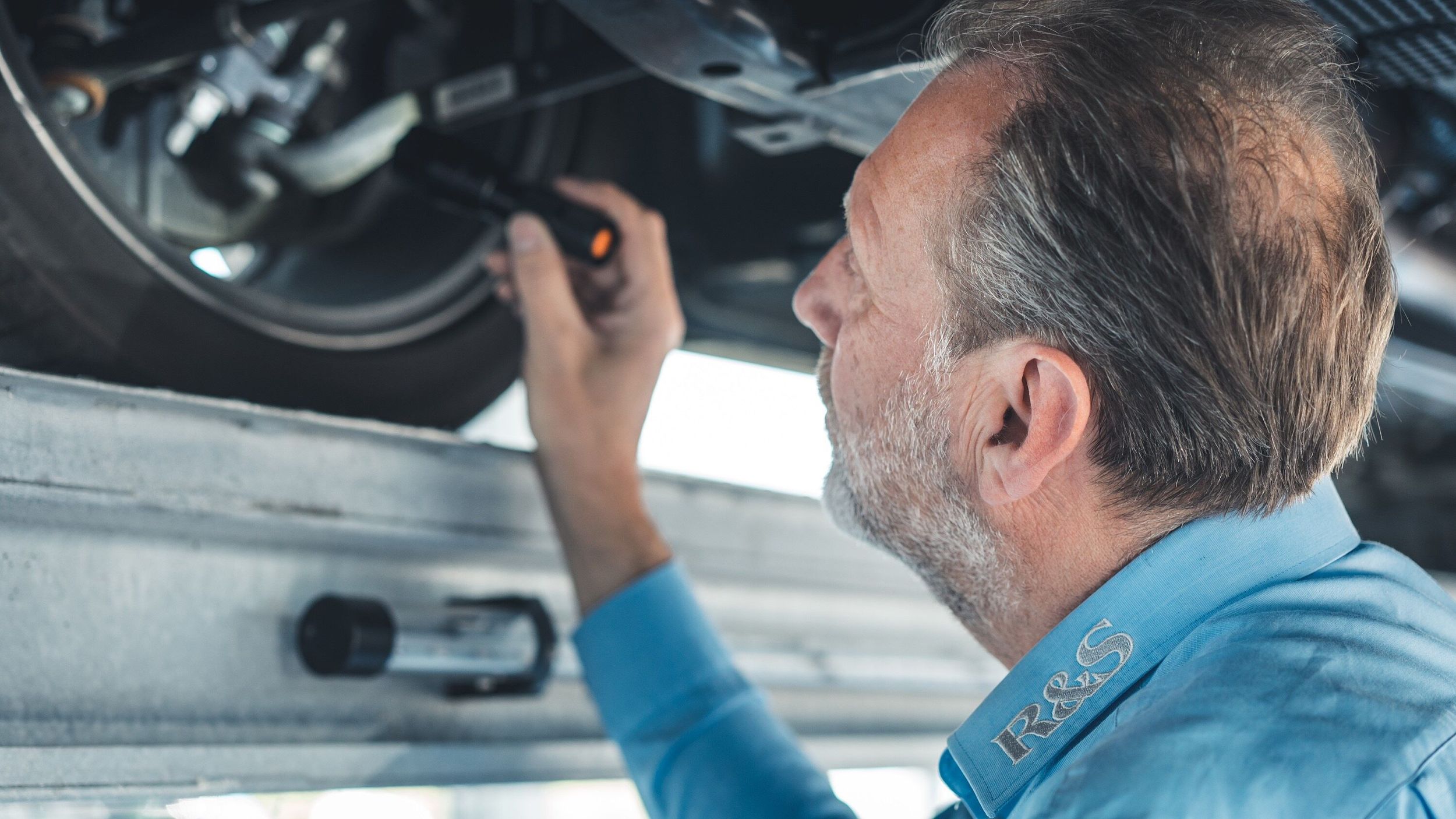 Mitarbeiter leuchtet unter ein Auto